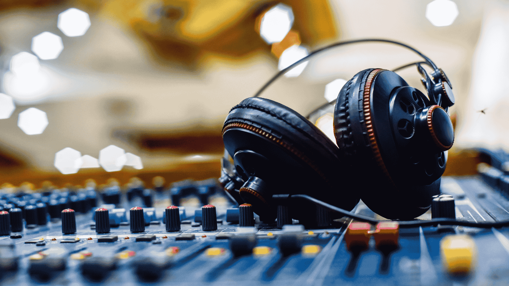 A close up of an audio mixing board and a set of headphones.