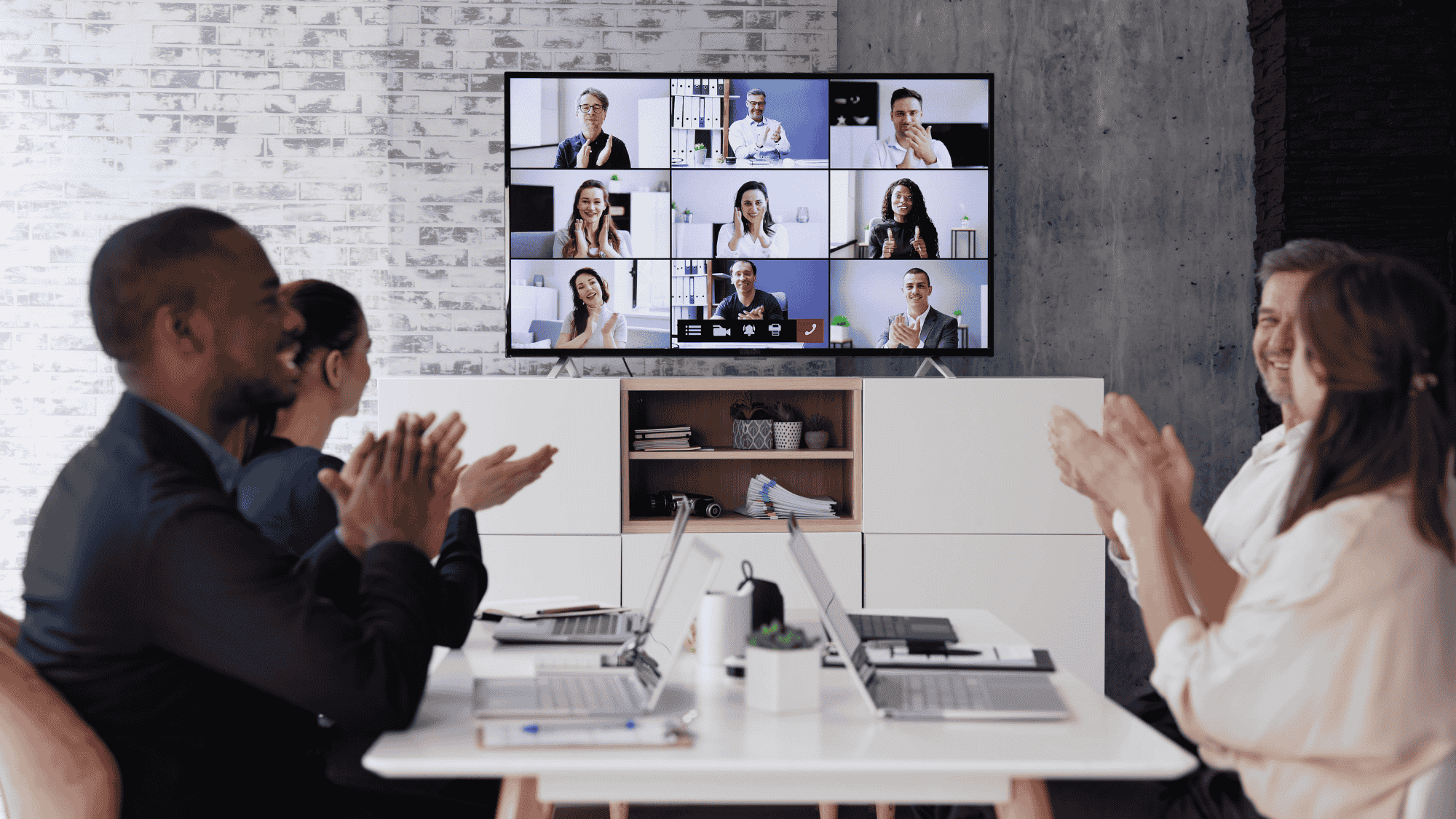 An office meeting in a room with a screen where others joined the meeting virtually.