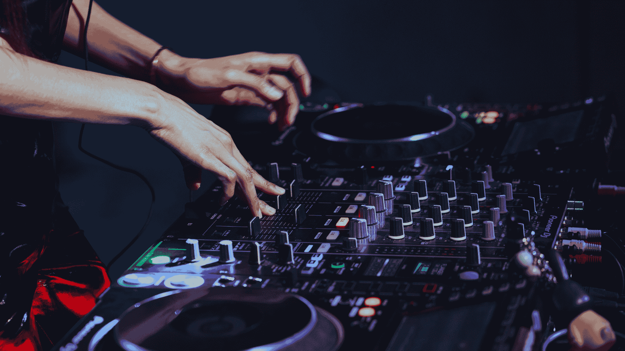 A close up of a DJ adjusting the levels on their soundboard.