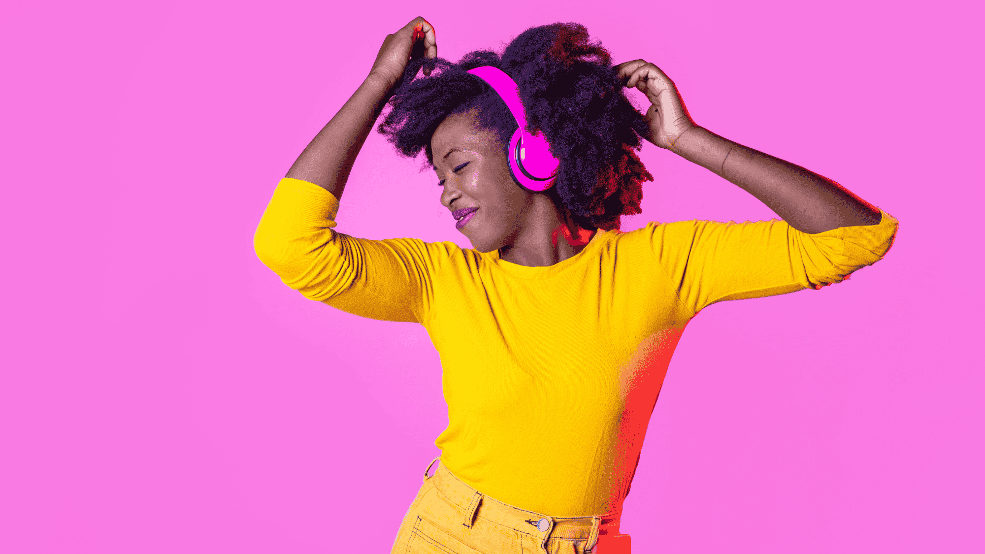 A woman wearing headphones dances while smiling.