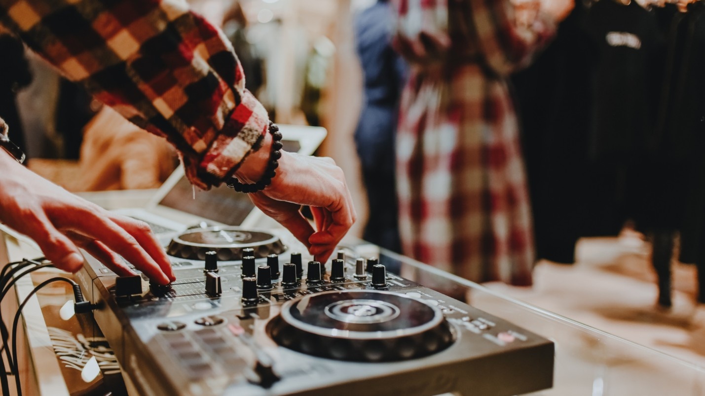 A DJ adjusts a dial on their audio board.