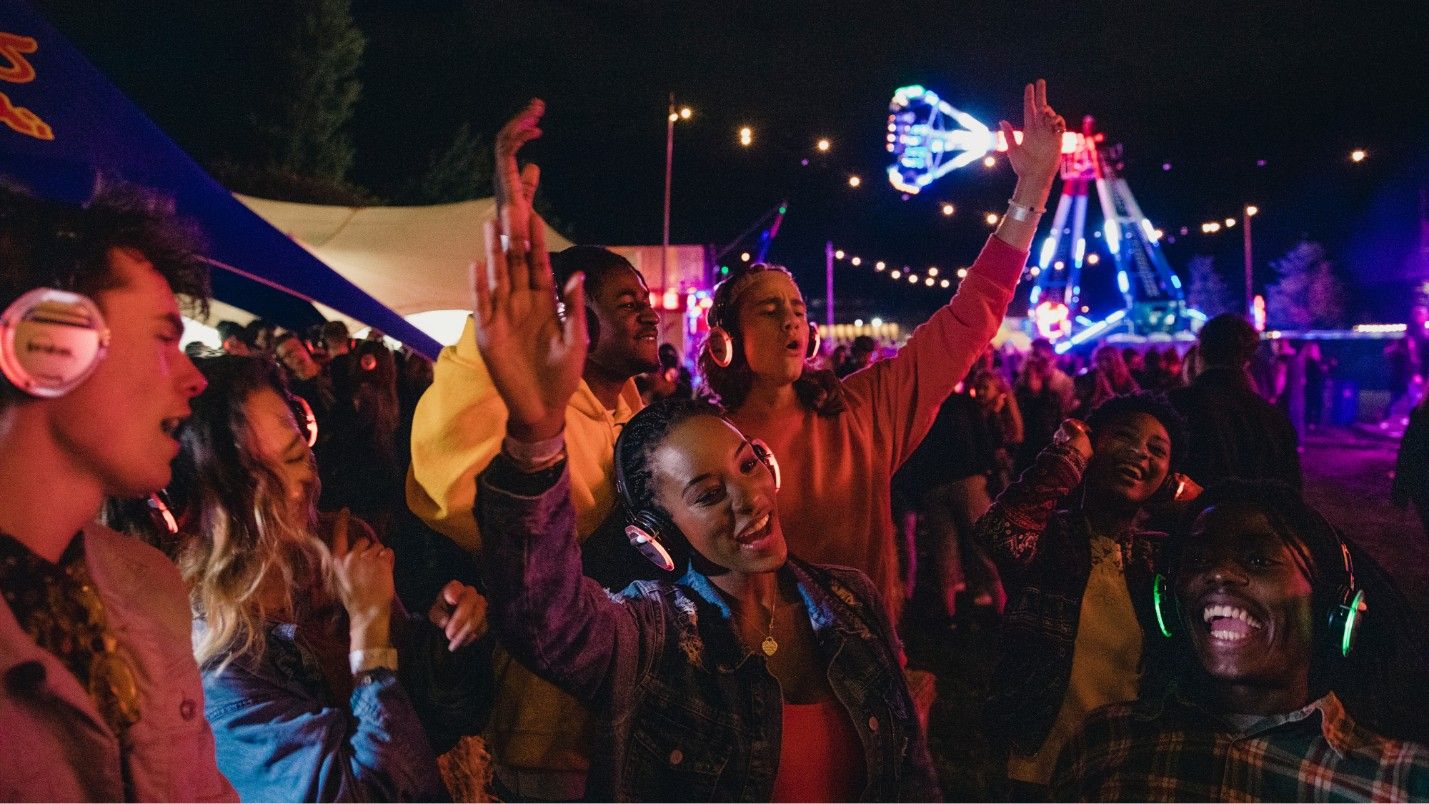 A group of people dance at a silent disco held outside.